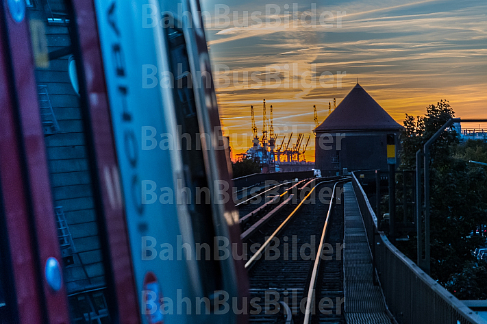 Ein U-Bahnzug der Baureihe DT5 bei Sonnenuntergang im Hamburger Hafen auf einem Viadukt