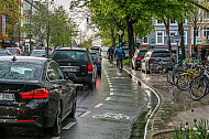 Fahrradfahrer fahren im Regen auf einer eigenen Fahrspur in der Osterstraße in Hamburg am Stau vorbei