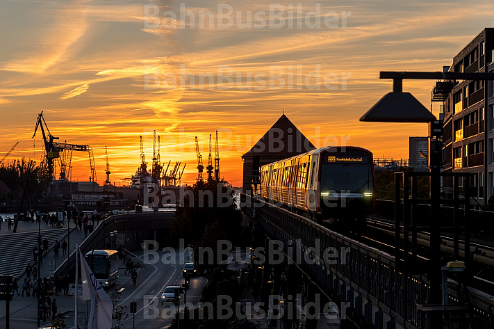Ein U-Bahnzug der Baureihe DT5 bei Sonnenuntergang im Hamburger Hafen auf einem Viadukt