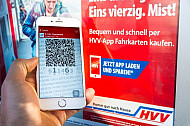 Ein Handyticket in der HVV-App vor einem Werbeplakat für E-Tickets