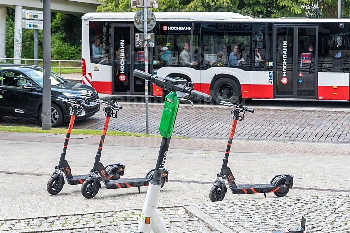 Mehrere E-Scooter verschiedener Leih-Anbieter stehen auf am Dammtor in Hamburg. Im Hintergrund ein Hochbahn-Bus.