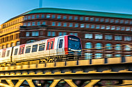 Ein U-Bahn-Zug vom Typ DT5 im goldenen Abendlicht auf einem Viadukt am Baumwall im Hamburger Hafen