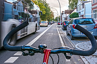 Ein Fahrradfahrer fährt auf einem vom Autoverkehr abgetrennten Radfahrstreifen in Hamburg - zwischen parkenden Autos und Busverkehr