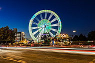 Autoverkehr vor dem Hamburger DOM mit Riesenrad im Abendlicht