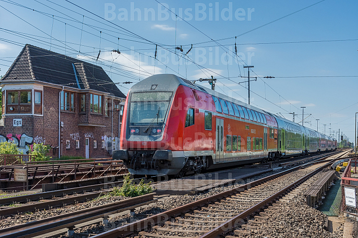 Ein moderner Doppelstockzug der Deutschen Bahn passiert ein altes Stellwerk in Hamburg-Eidelstedt