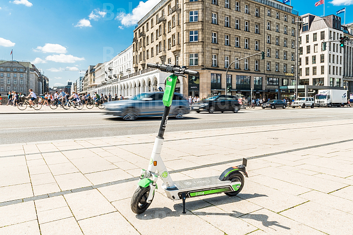 Ein E-Scooter steht am Jungfernstieg in Hamburg, im Hintergrund ein Auto