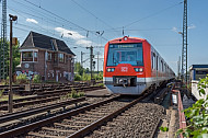 Ein S-Bahn-Zug der Baureihe 474 fährt in den Bahnhof Elbgaustraße ein. Im Hintergrund ein altes Stellwerk