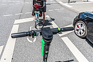 Ein E-Scooter steht auf einer Radfahrspur in Hamburg an einer Ampel hinter einem Radfahrer