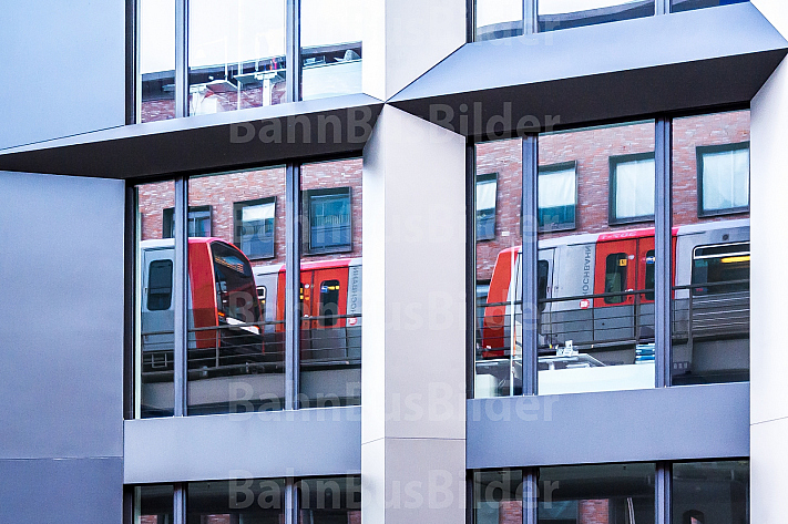 Zwei U-Bahnzüge vom Typ DT5 spiegeln sich in einem Bürogebäude in Hamburg