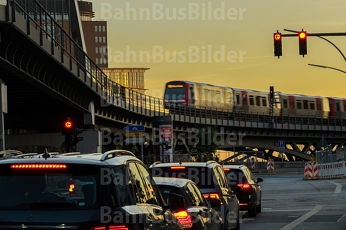 Eine Hamburger U-Bahn vom Typ DT5 fährt auf einem Viadukt im Hafen, während sich unten der Autoverkehr staut