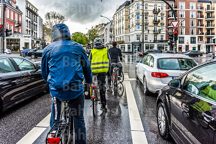 Fahrradfahrer stehen im Regen auf einer Radfahrspur an einer Ampel in Hamburg