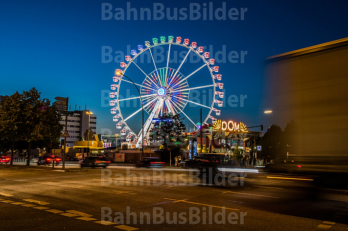 Autoverkehr vor dem Hamburger DOM mit Riesenrad im Abendlicht