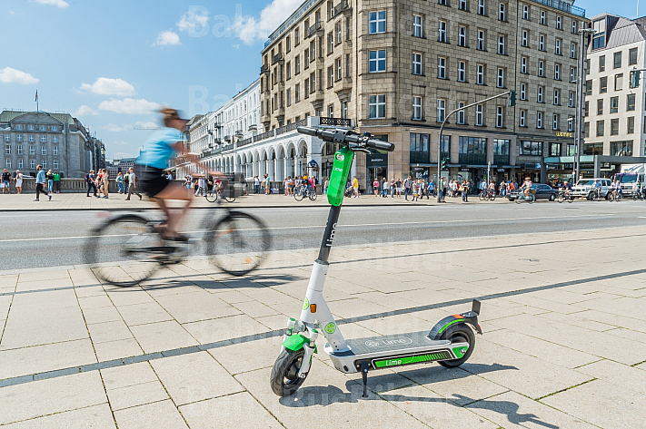 Ein E-Scooter steht am Jungfernstieg in Hamburg, im Hintergrund ein Fahrradfahrer